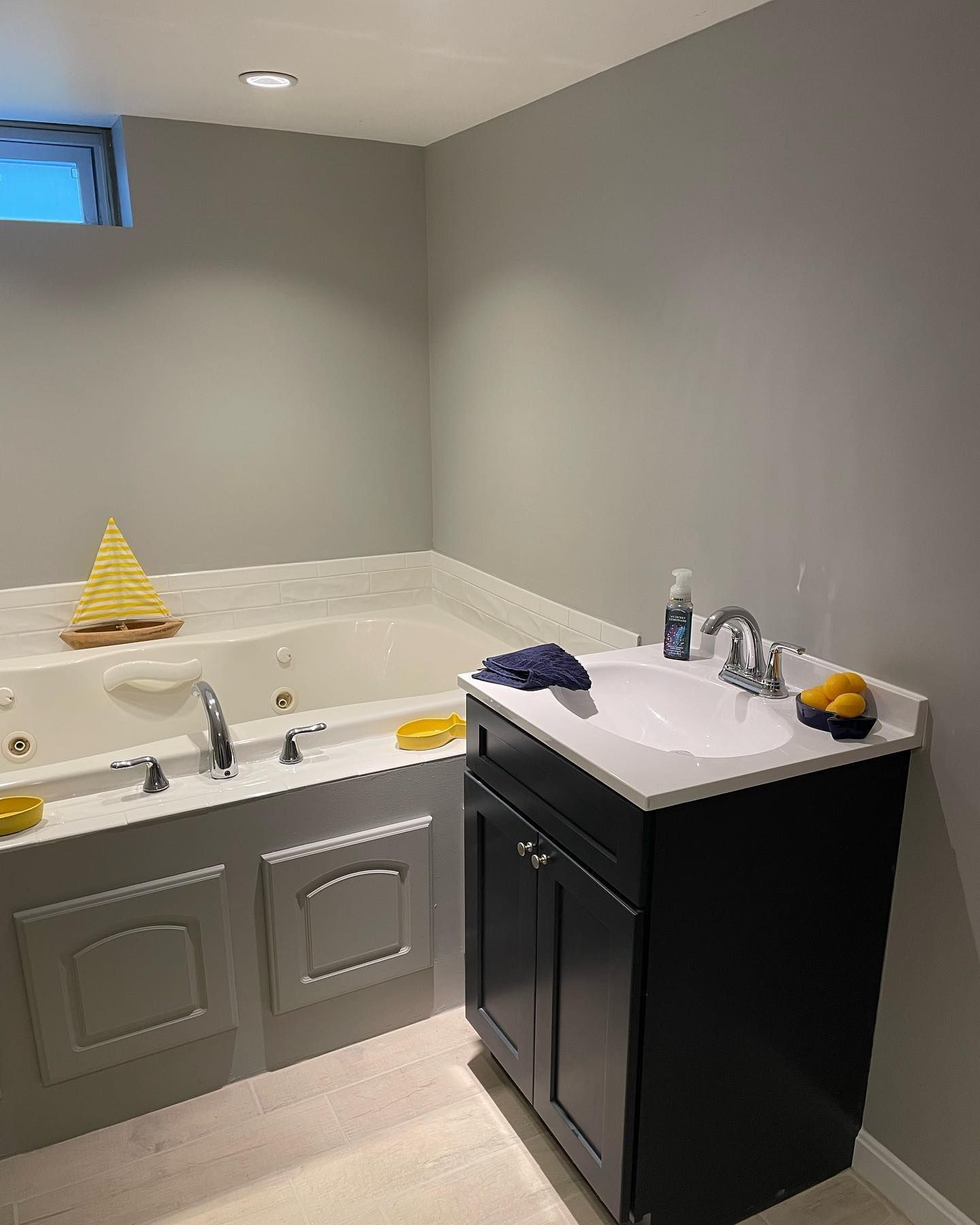 Bathroom with a jacuzzi tub and a black vanity, light grey walls.