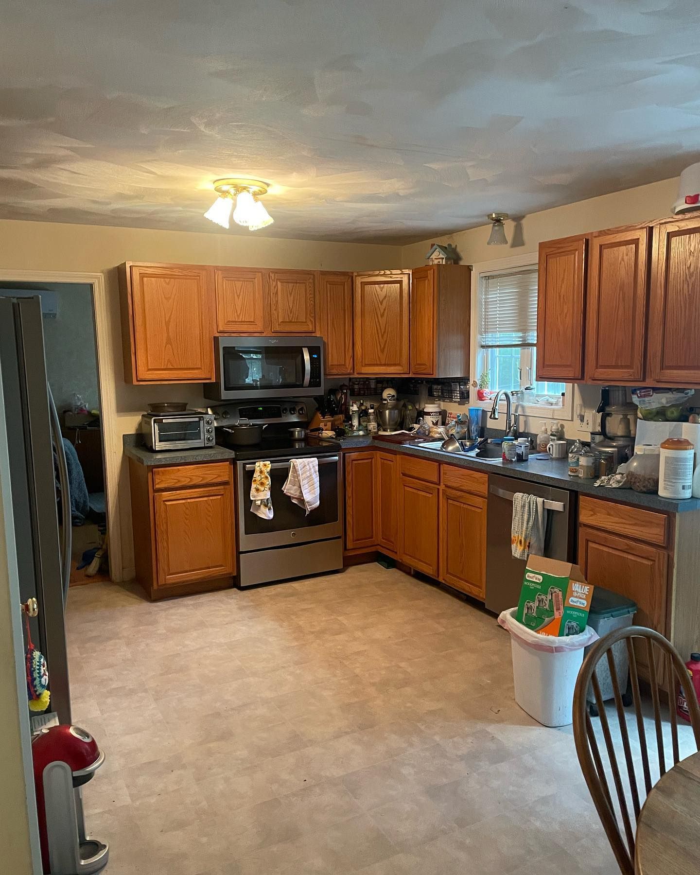 Kitchen with brown cabinets, stainless steel appliances, and beige linoleum flooring.