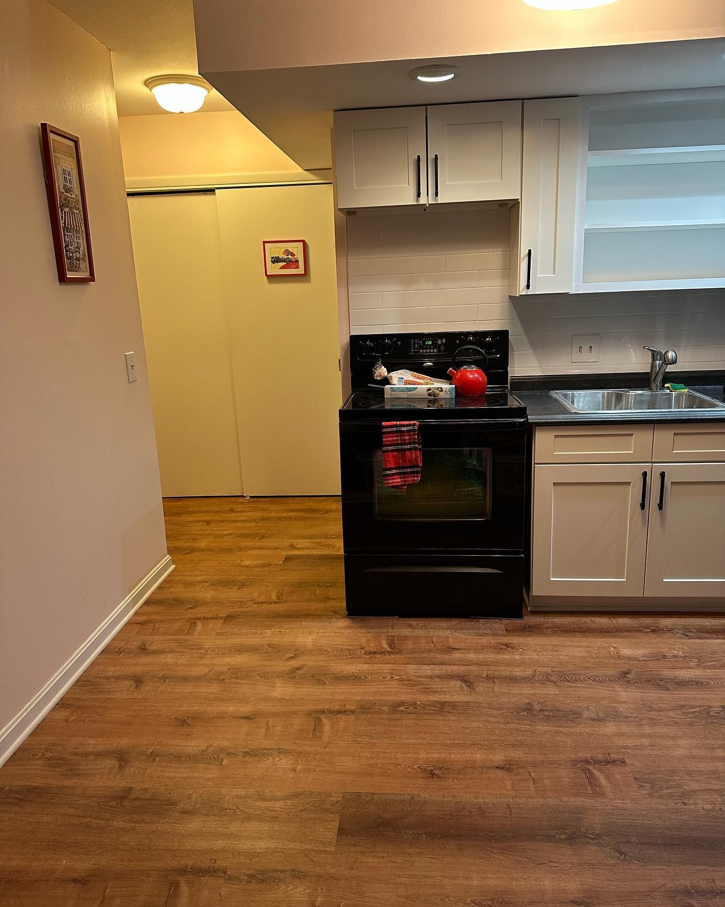 Kitchen with black oven, white cabinets, and wood-look flooring. Entryway with a door is visible.