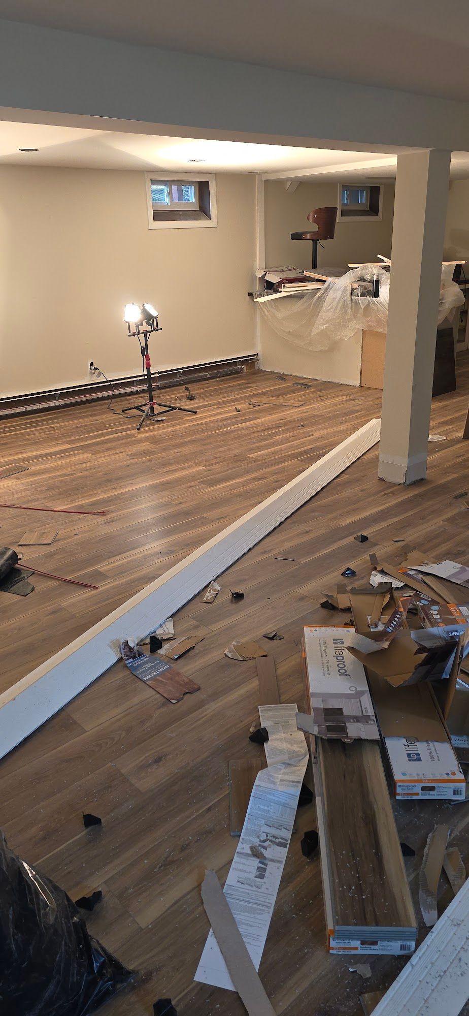 Room with wooden floor partially installed during renovation, debris on floor.