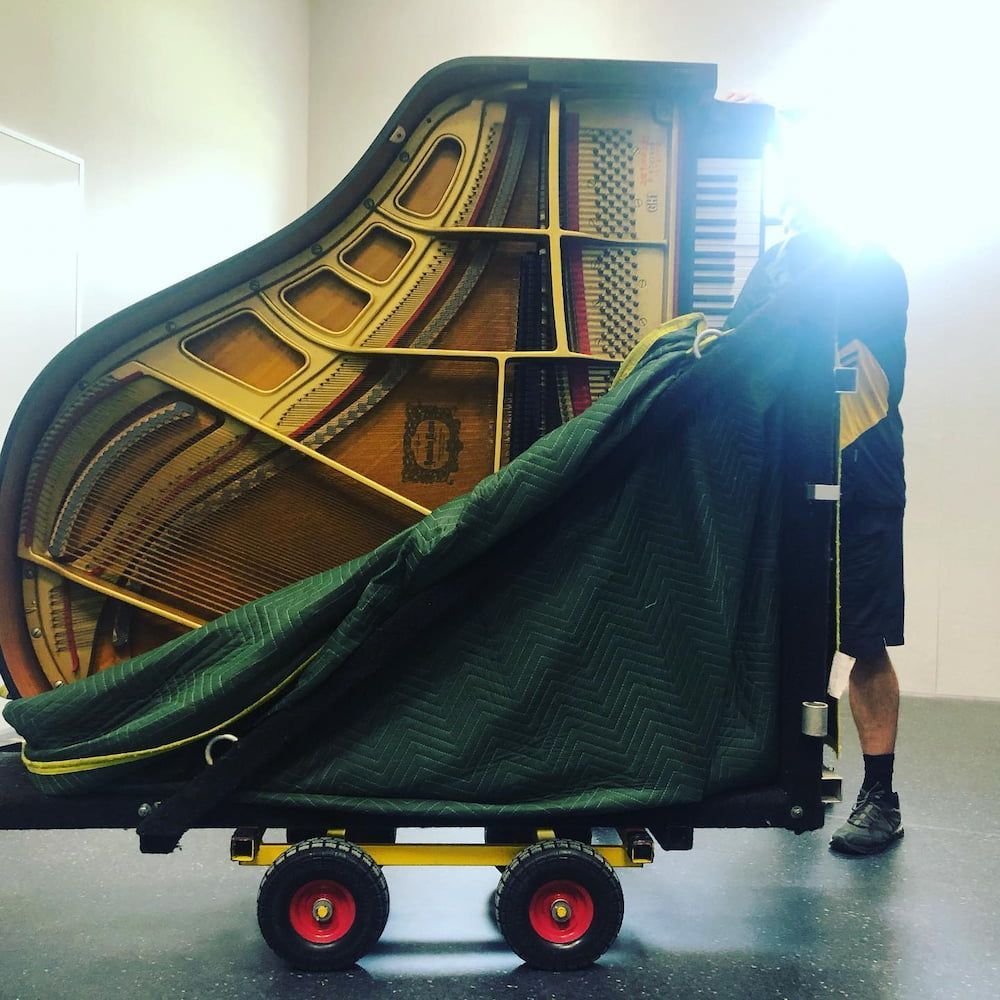 A Man is Carrying a Piano on a Cart — FNQ Furniture Removals in Stratford, QLD