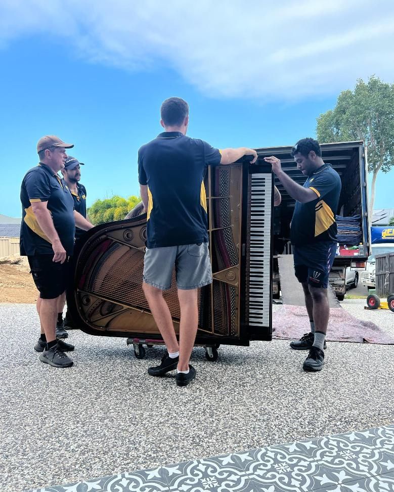 A Group of Men Are Moving a Piano Out of a Truck — FNQ Furniture Removals in Mareeba, QLD