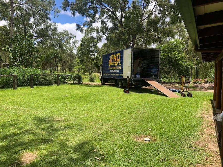 A Moving Truck is Parked in a Grassy Field Next to a House — FNQ Furniture Removals in Tablelands, QLD