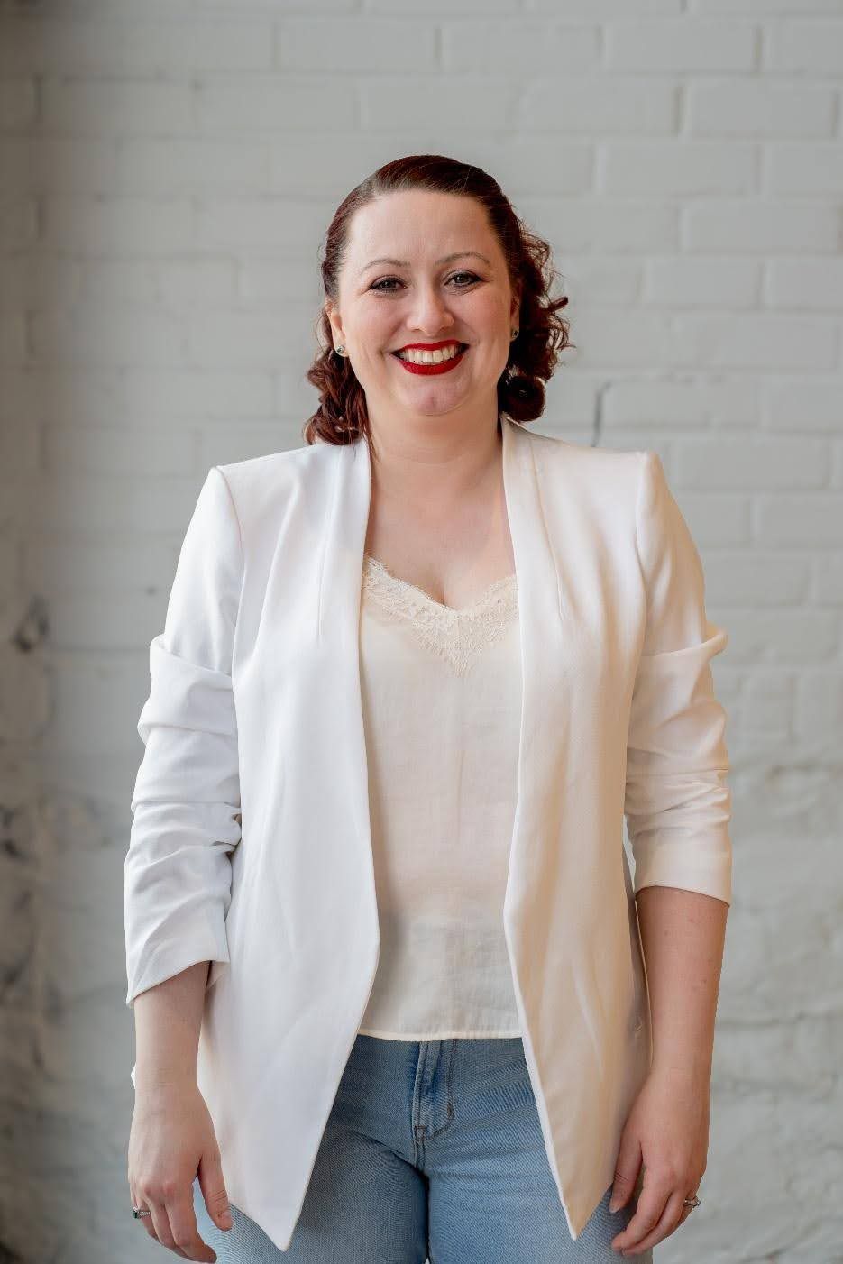 A woman is sitting at a table wearing a necklace and smiling.