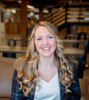 A woman wearing a necklace and a black jacket is smiling