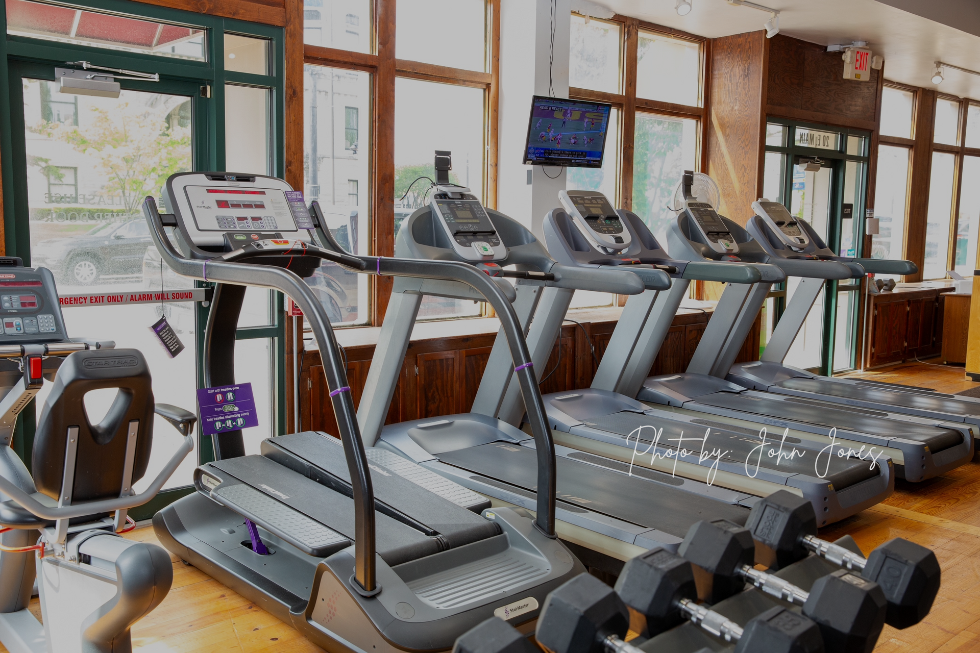 A gym with a lot of treadmills and dumbbells