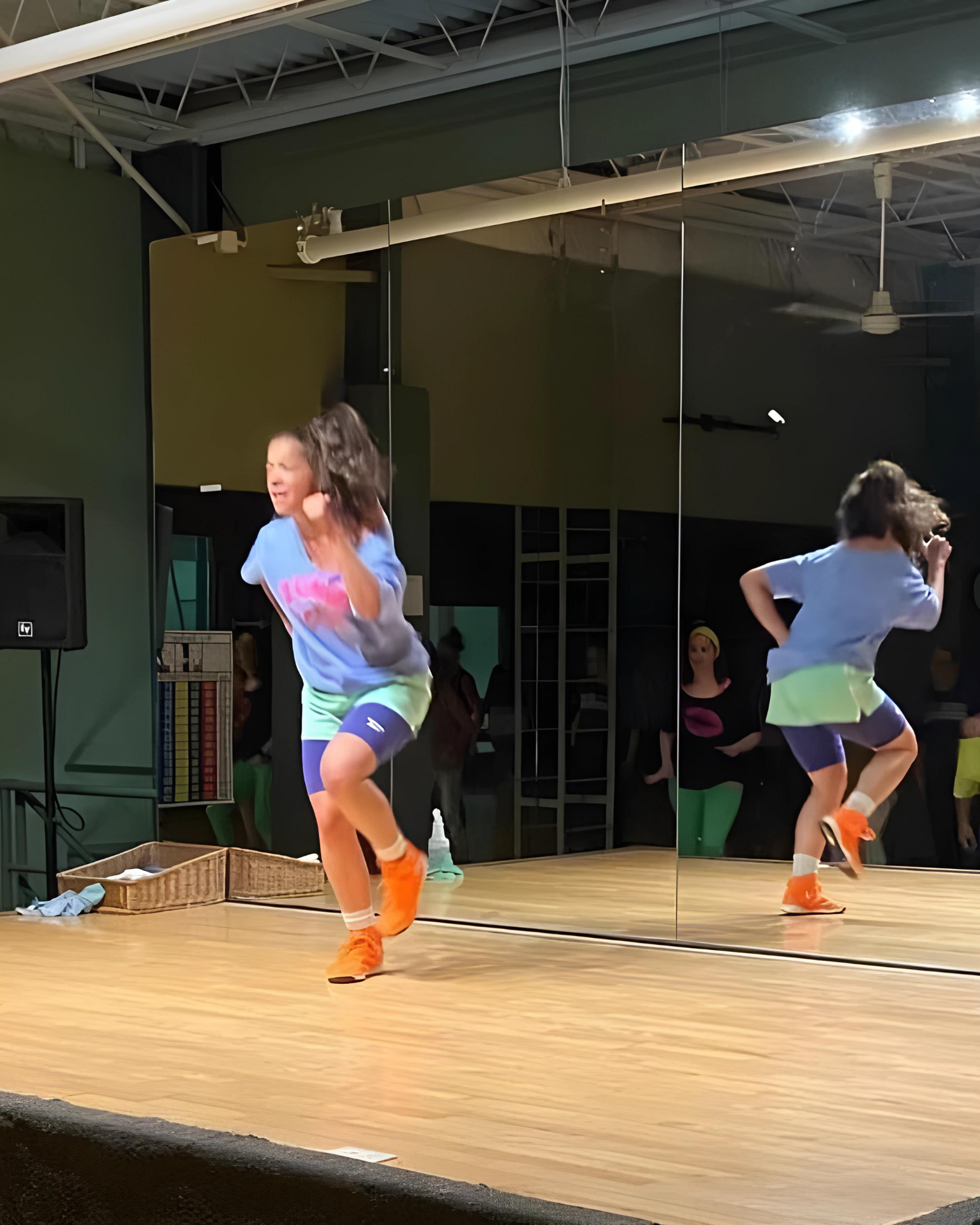 Two girls are dancing on a stage in front of a mirror.