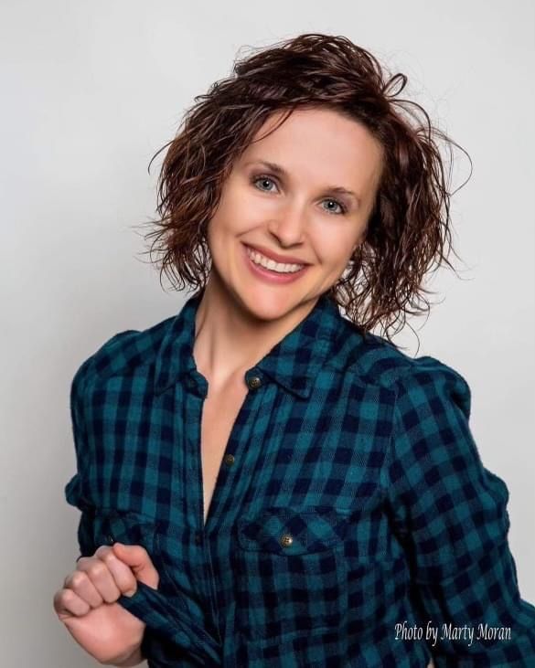 A woman in a plaid shirt is smiling for the camera