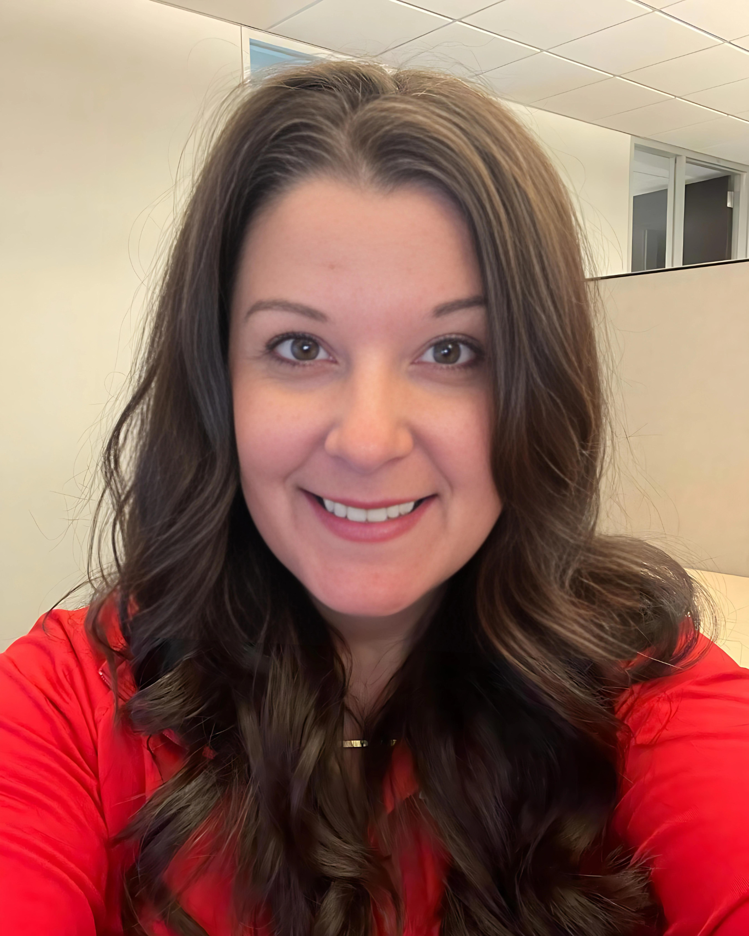 A woman in a red shirt is smiling for the camera.