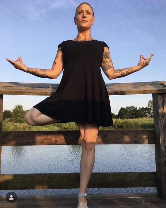 A woman in a black dress is doing a yoga pose