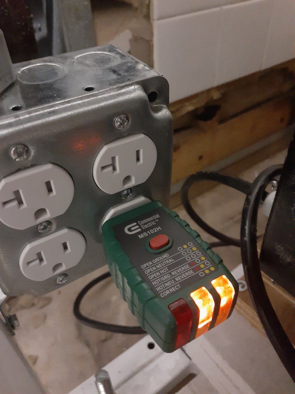 A green device is plugged into an electrical outlet