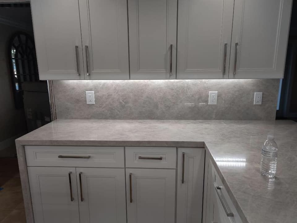 A kitchen with white cabinets and a granite counter top.