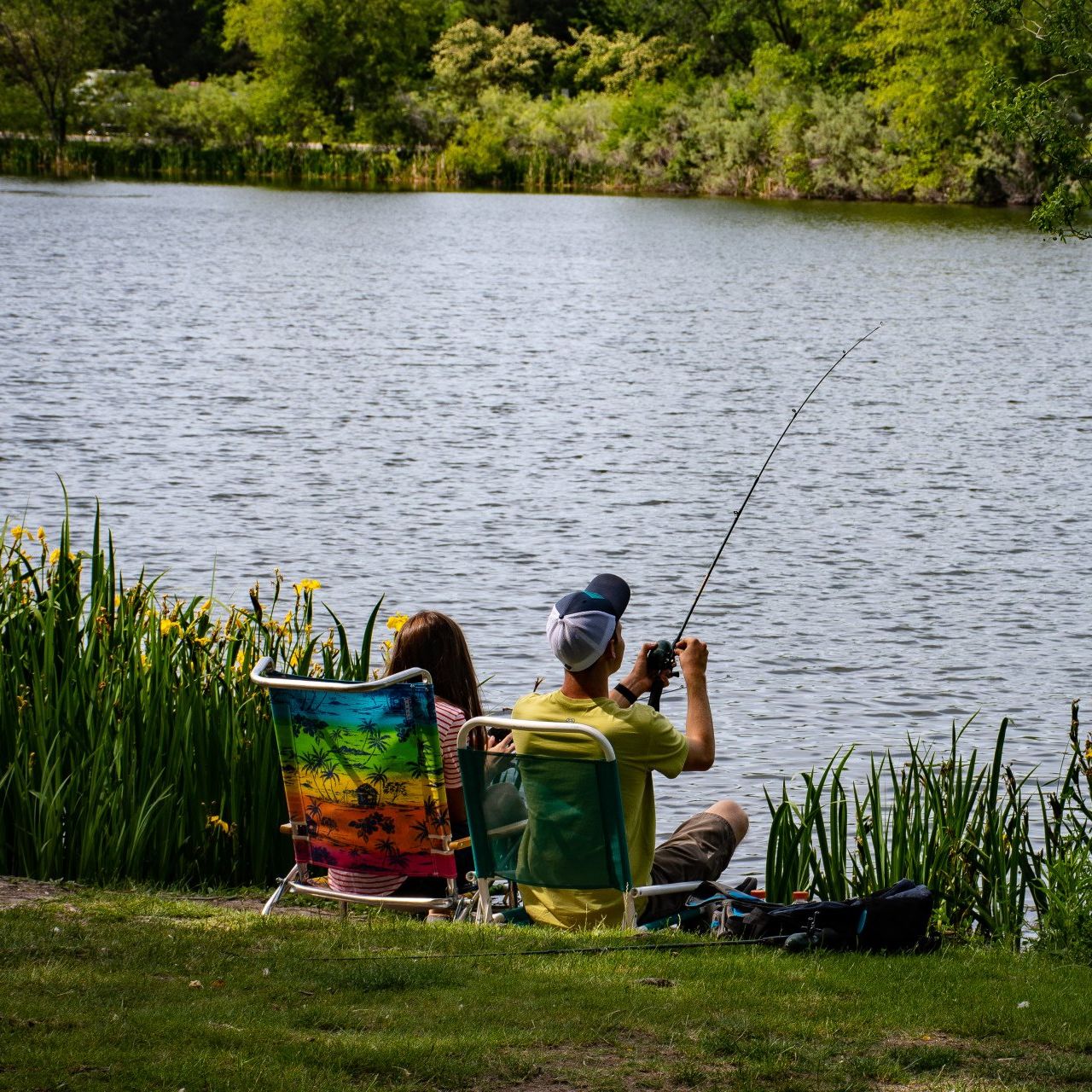 couple sitting by lake fishing