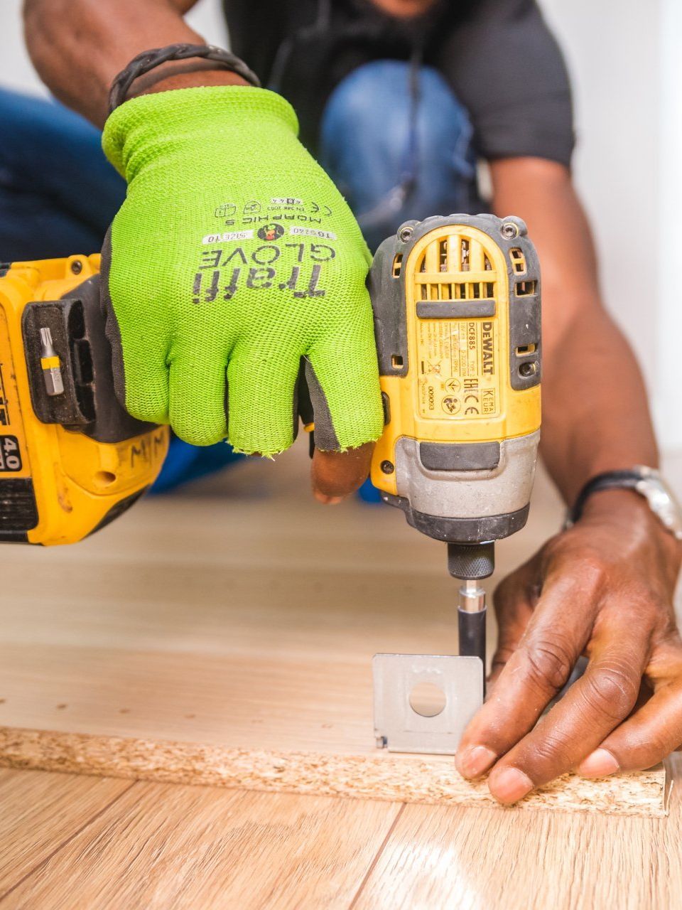 A man is using a drill to drill a hole in a piece of wood.