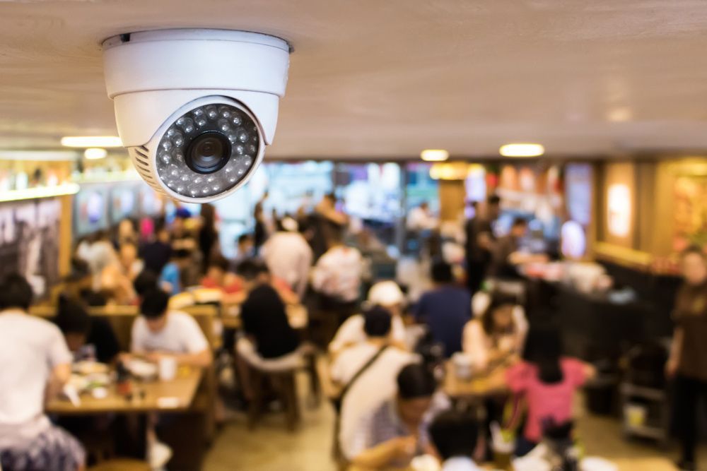 A Security Camera Is Hanging From The Ceiling Of A Restaurant — On Guard Security & Communications In Wallsend, NSW