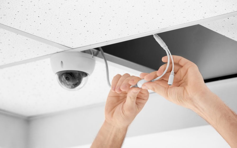 A Person Is Installing A Security Camera On The Ceiling — On Guard Security & Communications In Wallsend, NSW