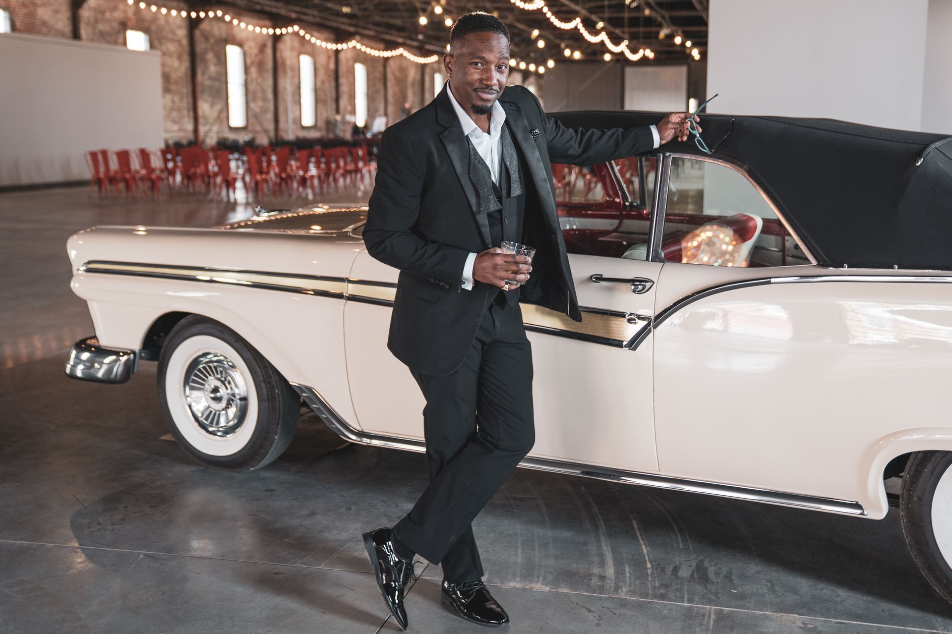 A man in a tuxedo is standing next to a white car.