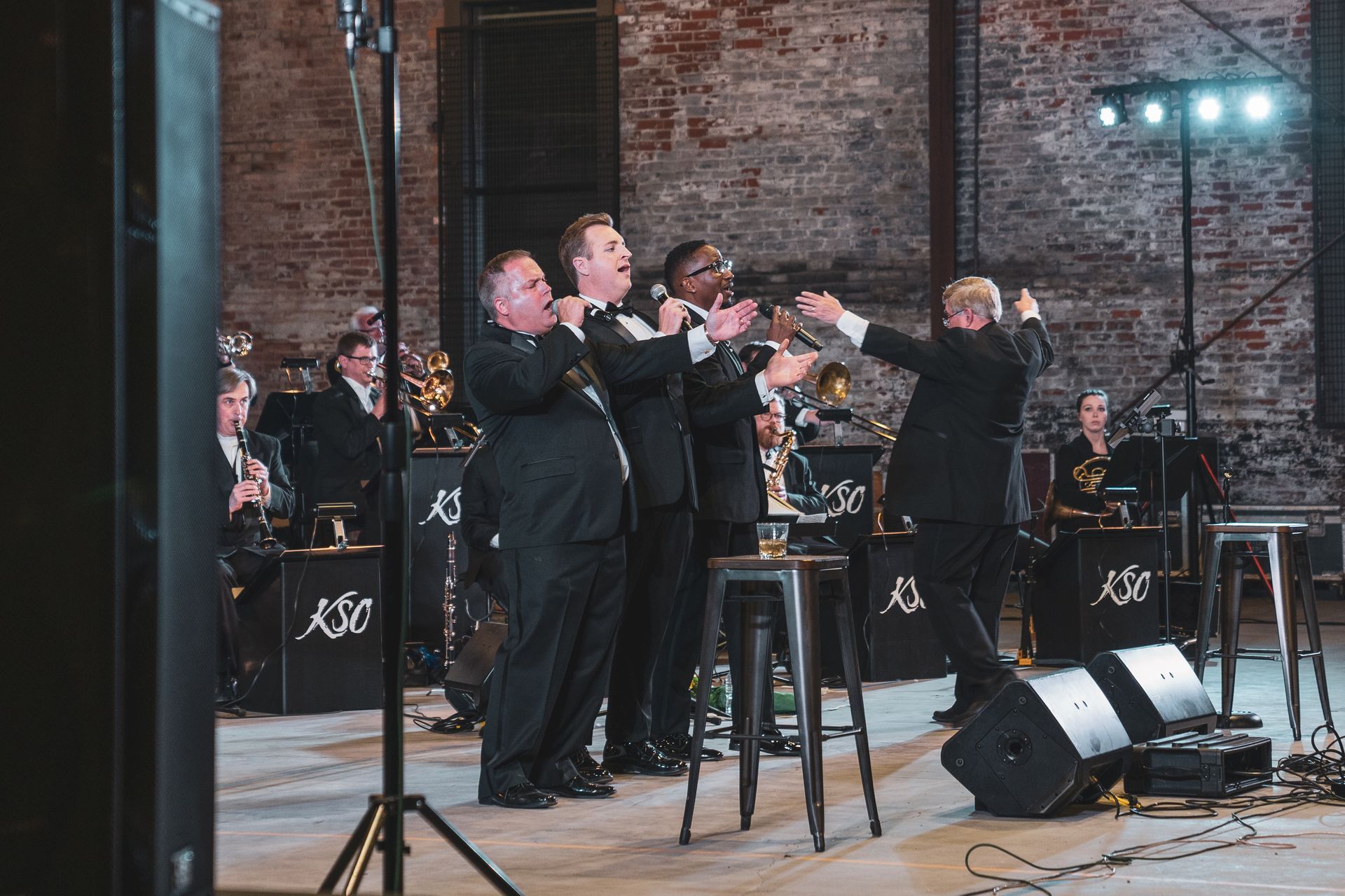 A group of men in suits are standing on a stage playing instruments.