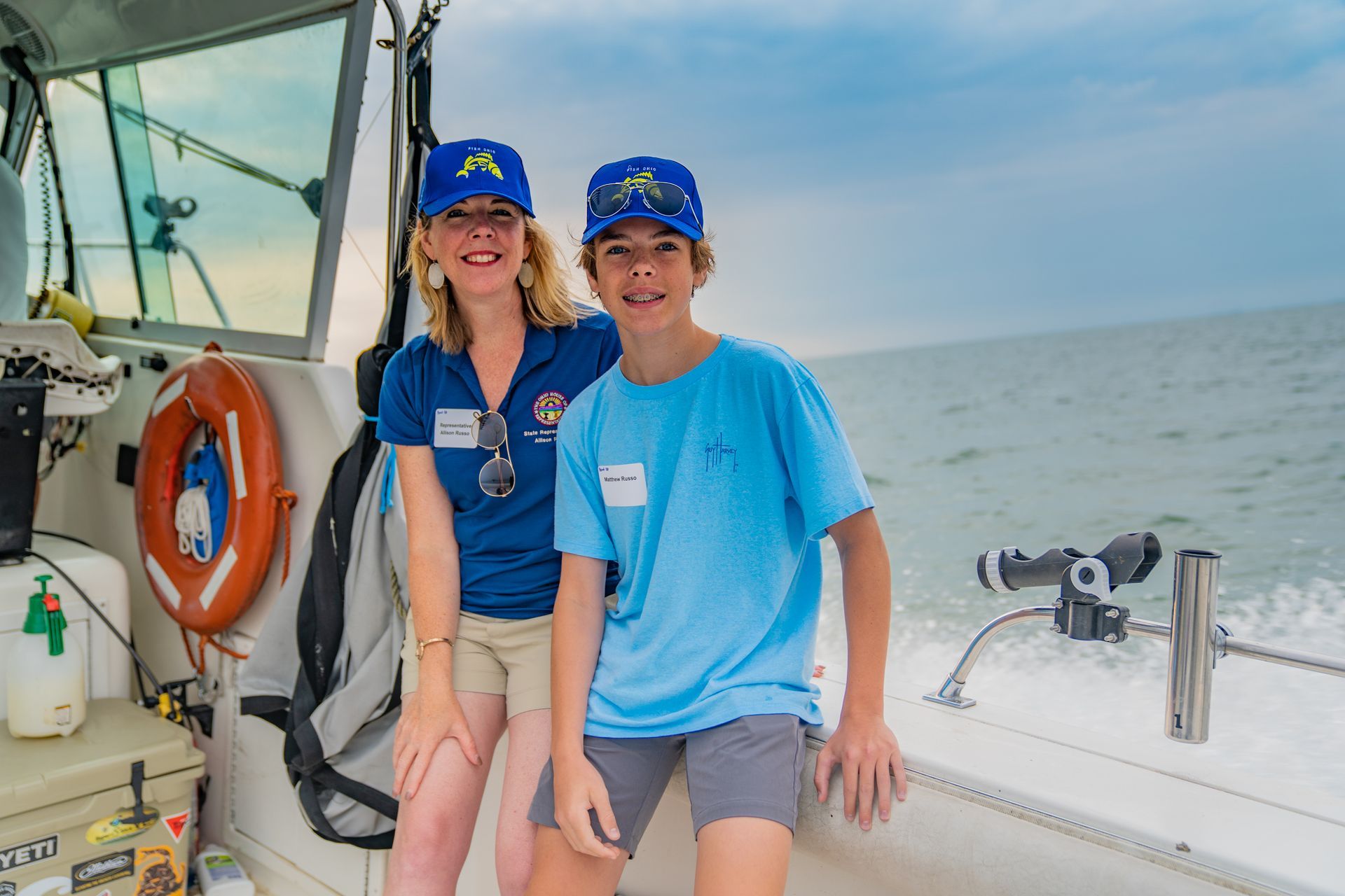 A woman and a boy are sitting on the side of a boat.