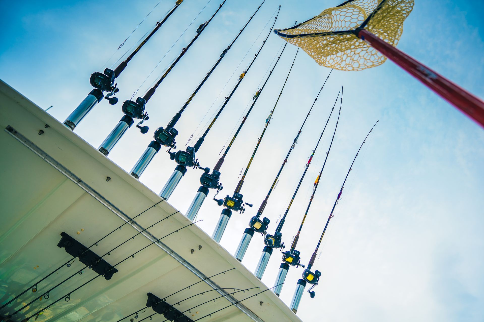 A bunch of fishing rods are lined up on a boat.