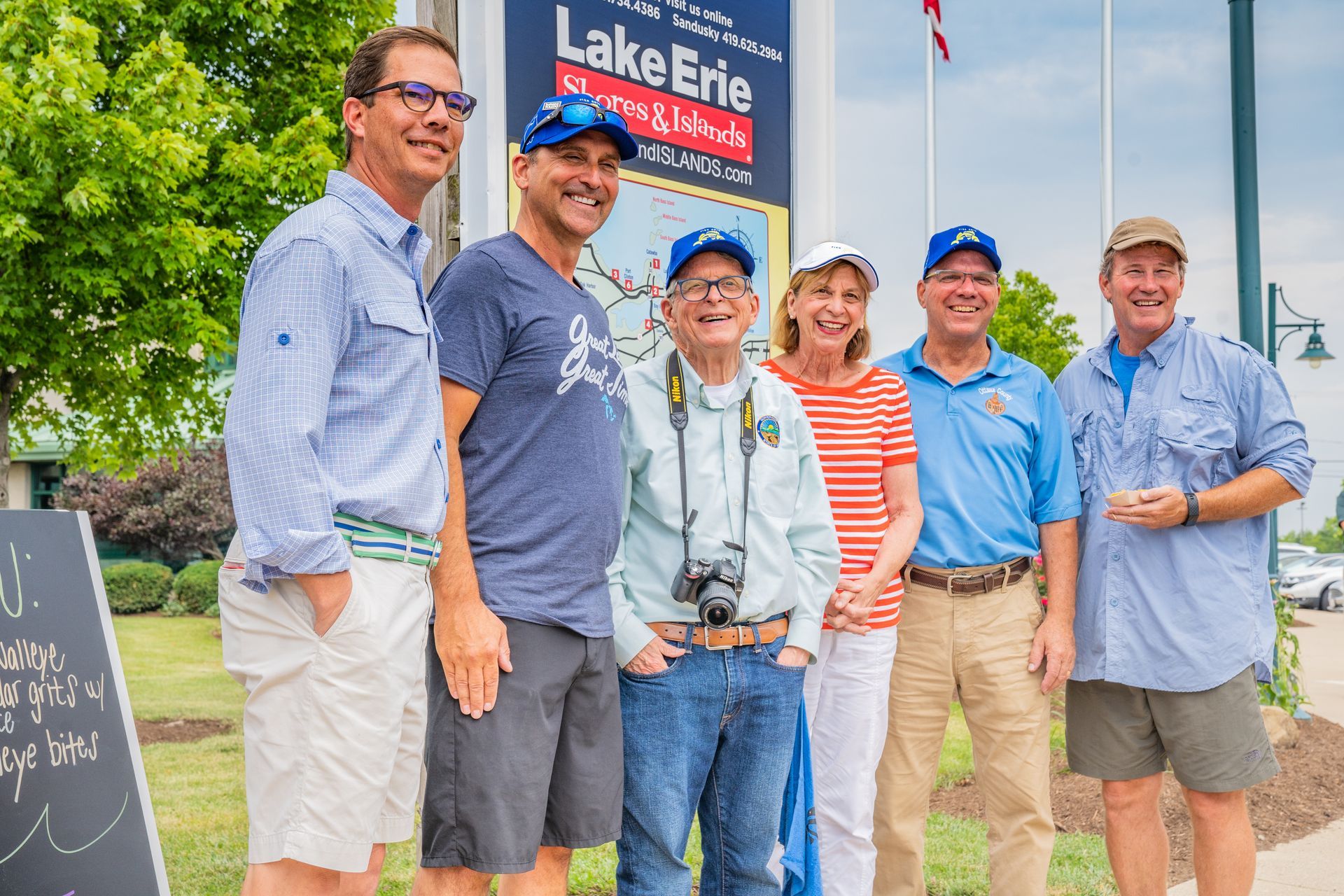 A group of people are posing for a picture in front of a lake erie sign.