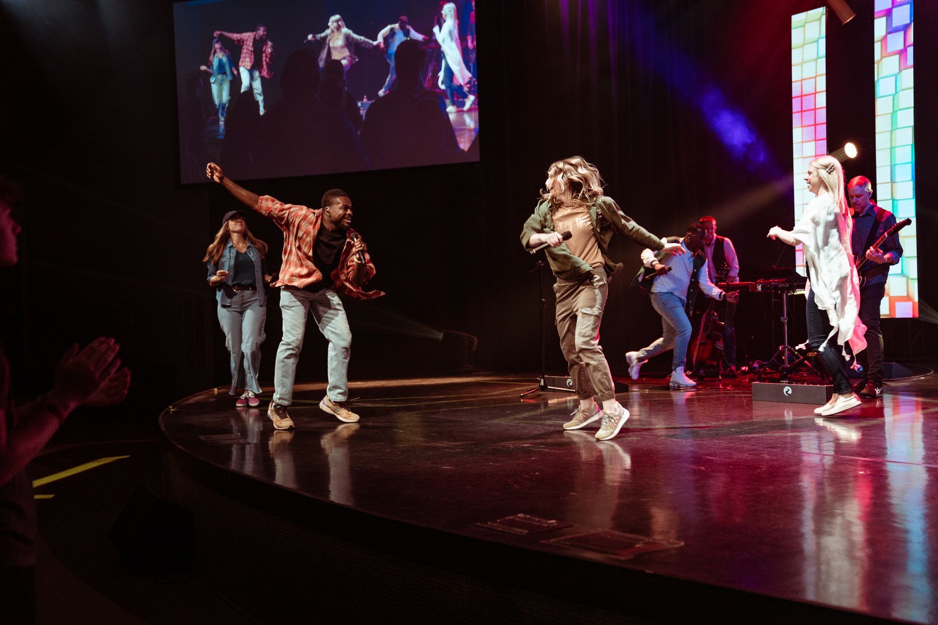A group of people are dancing on a stage in front of a crowd.