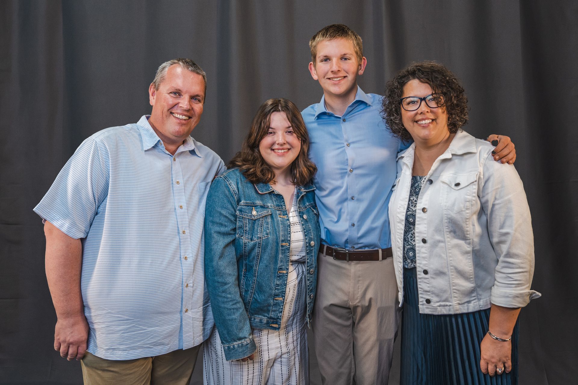 A family posing for a picture together in front of a black curtain.