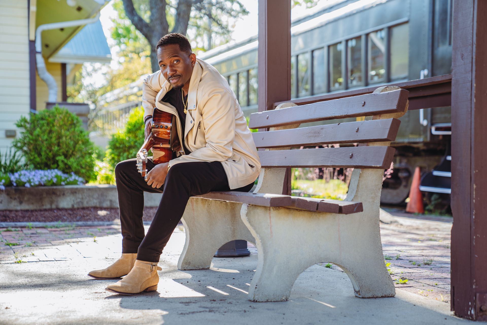A man is sitting on a bench in front of a train.