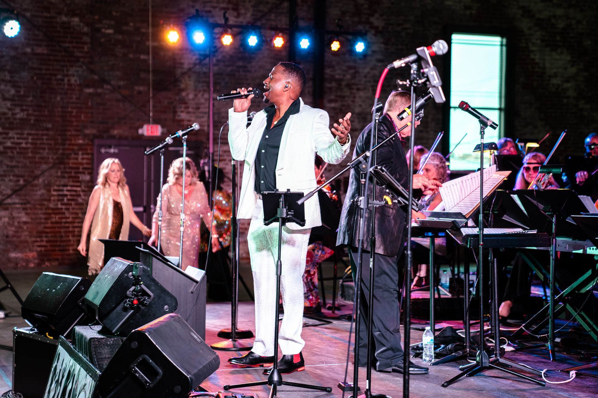A group of people are singing into microphones on a stage.
