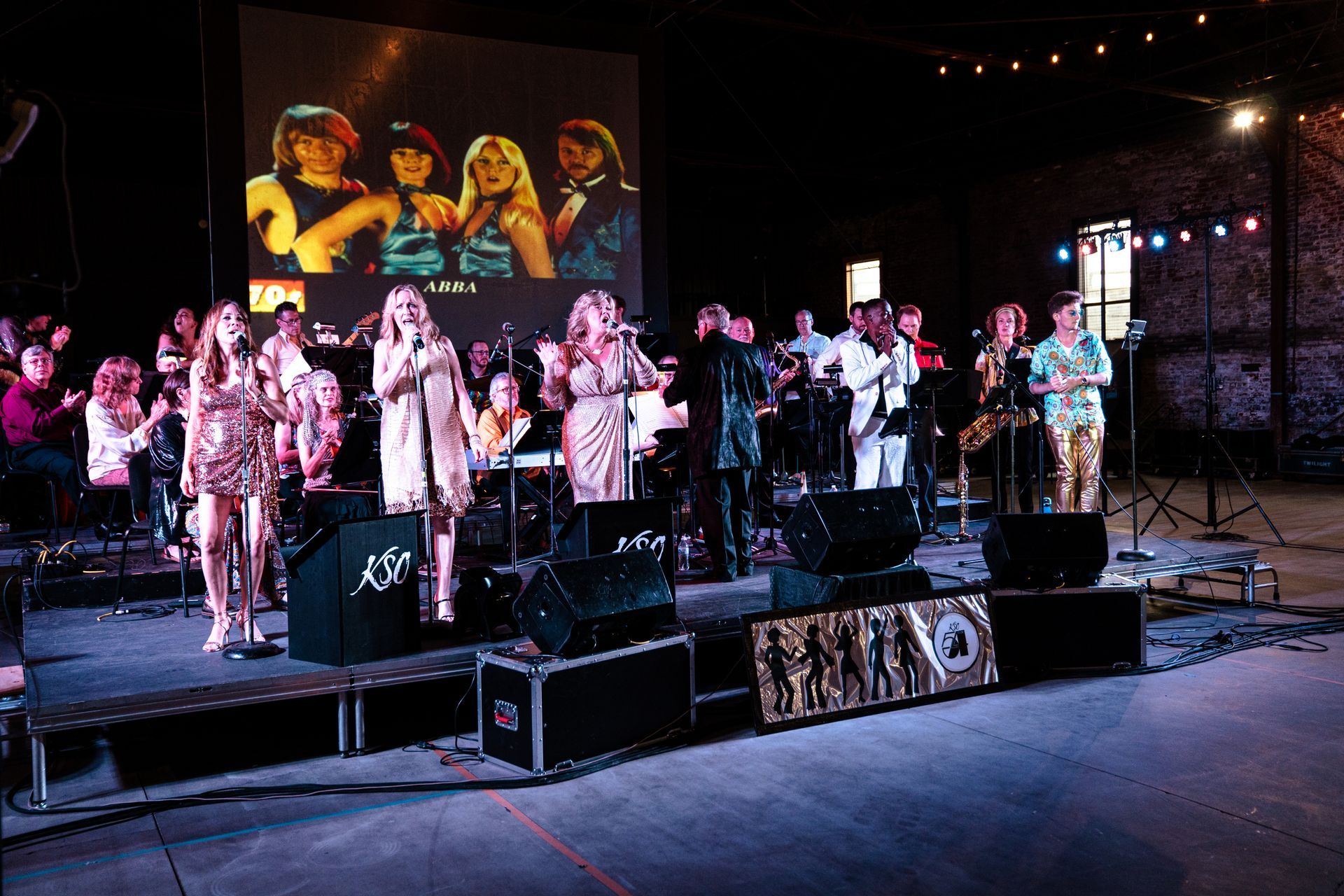 A group of people are standing on a stage in front of a large screen.