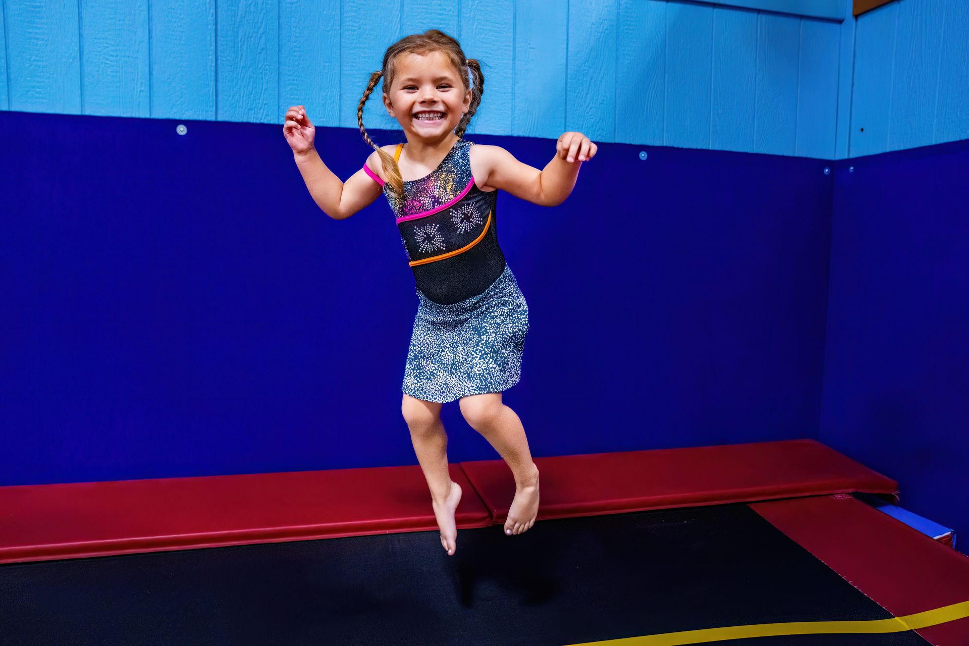 A little girl is jumping on a trampoline.