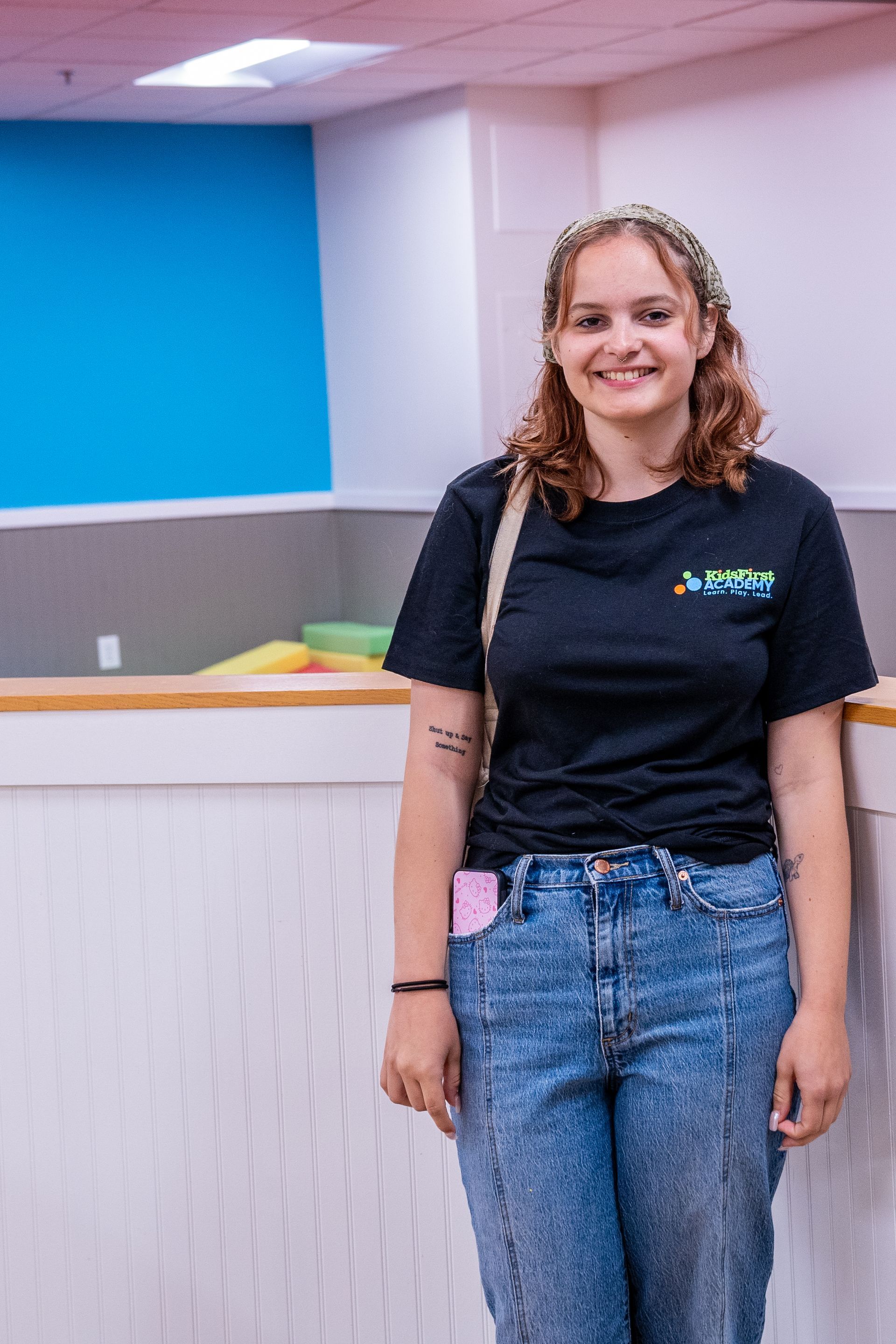A woman in a black shirt and blue jeans is standing in a room.