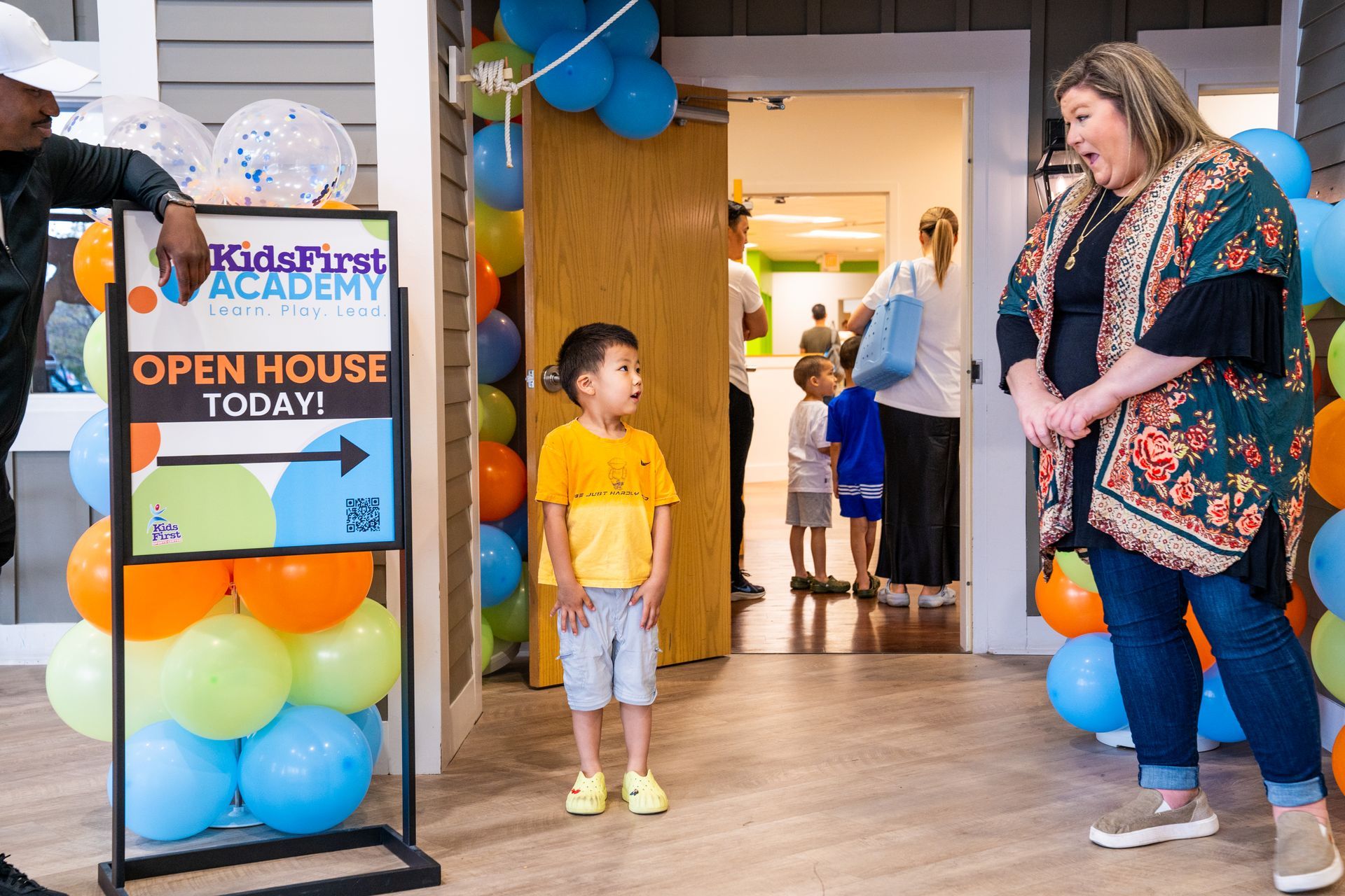 A woman and a boy are standing in front of a sign that says open house today.