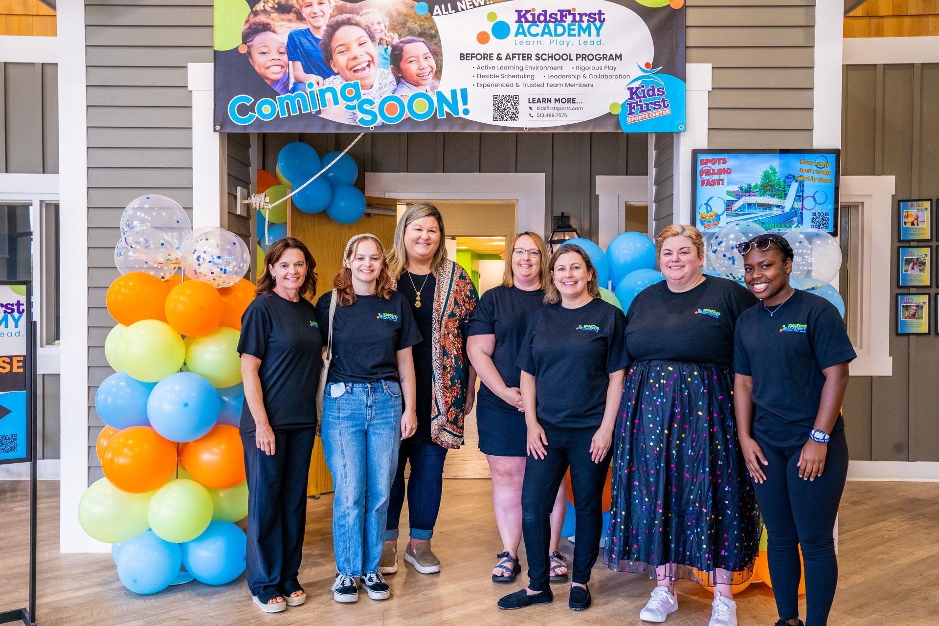 A group of women are posing for a picture in front of balloons.