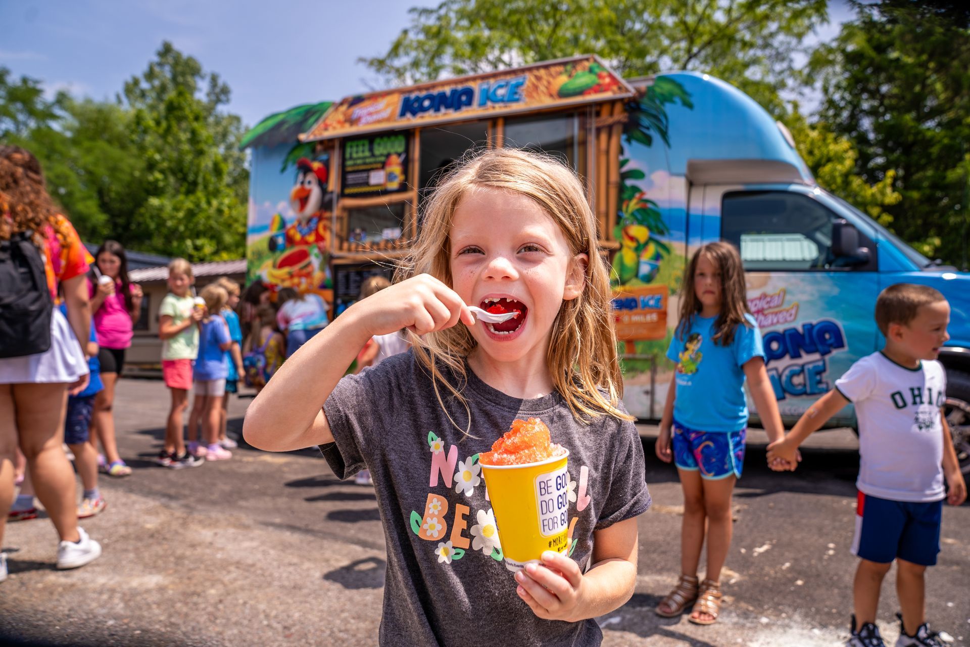 A little girl is eating ice cream from an ice cream truck.
