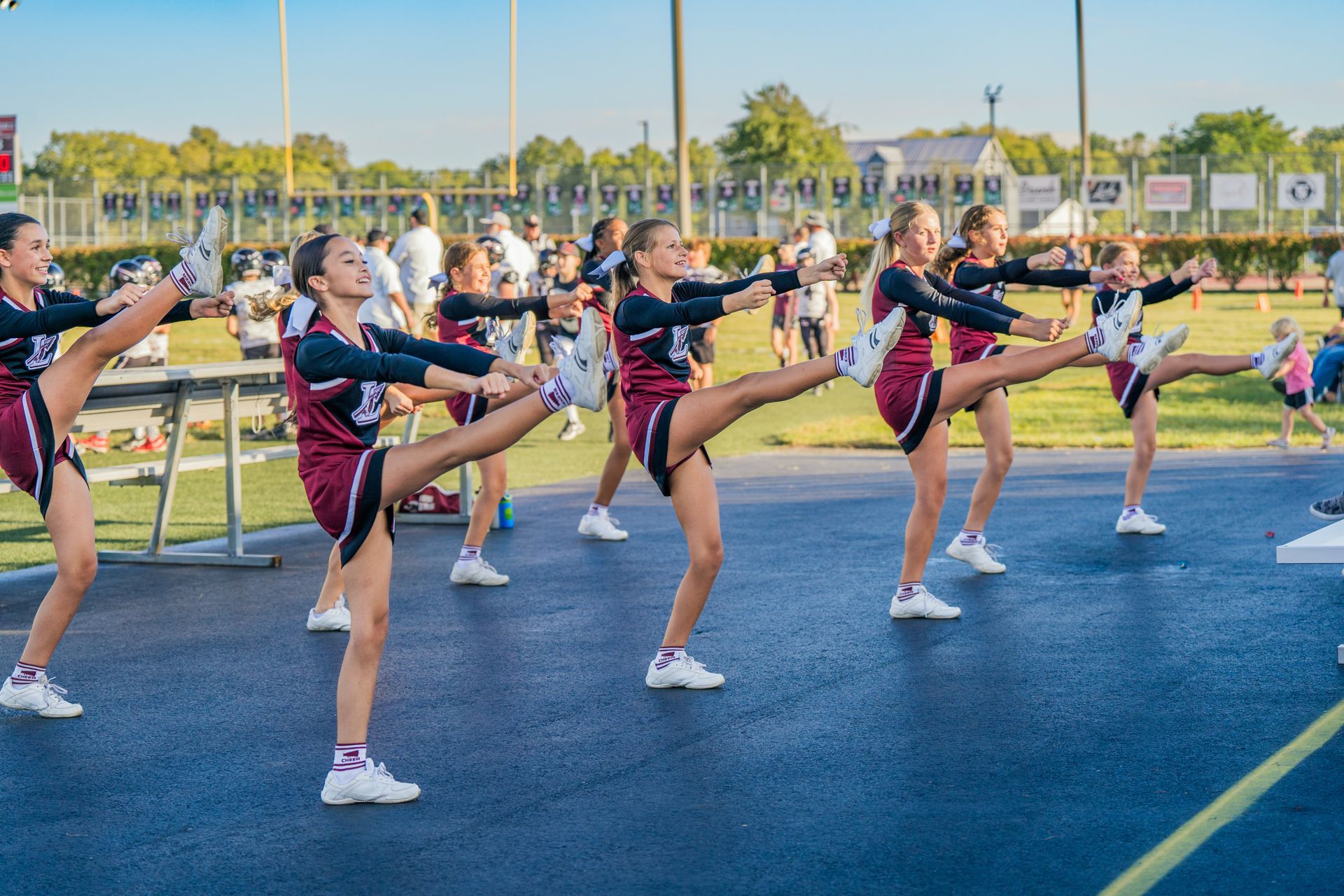 A group of cheerleaders are stretching their legs on a track.
