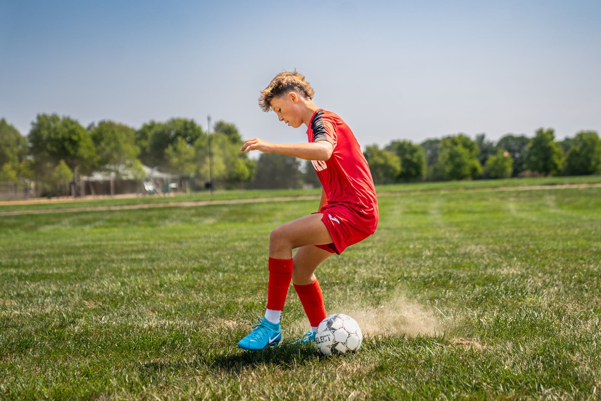 A young boy is kicking a soccer ball on a field.