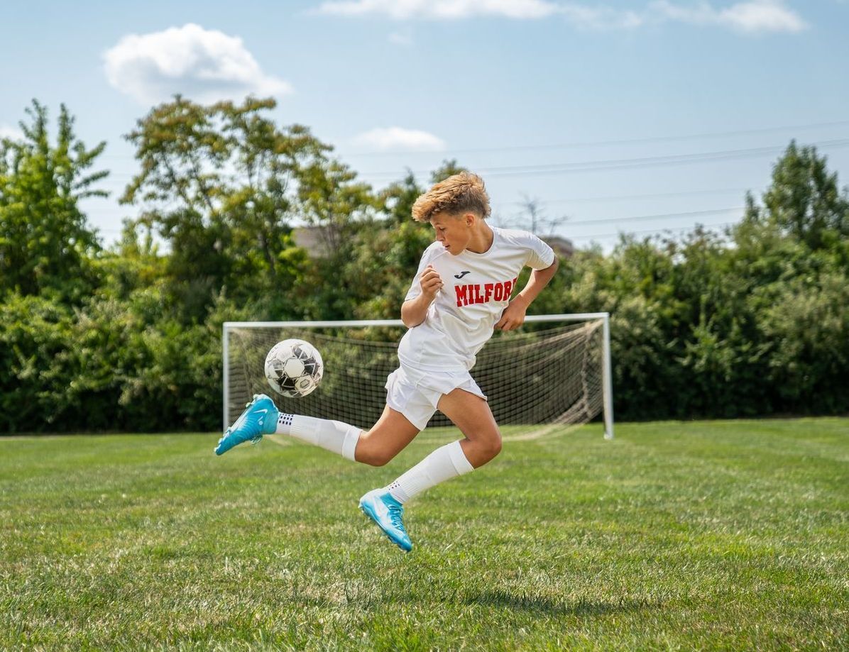 A young boy is kicking a soccer ball on a field.