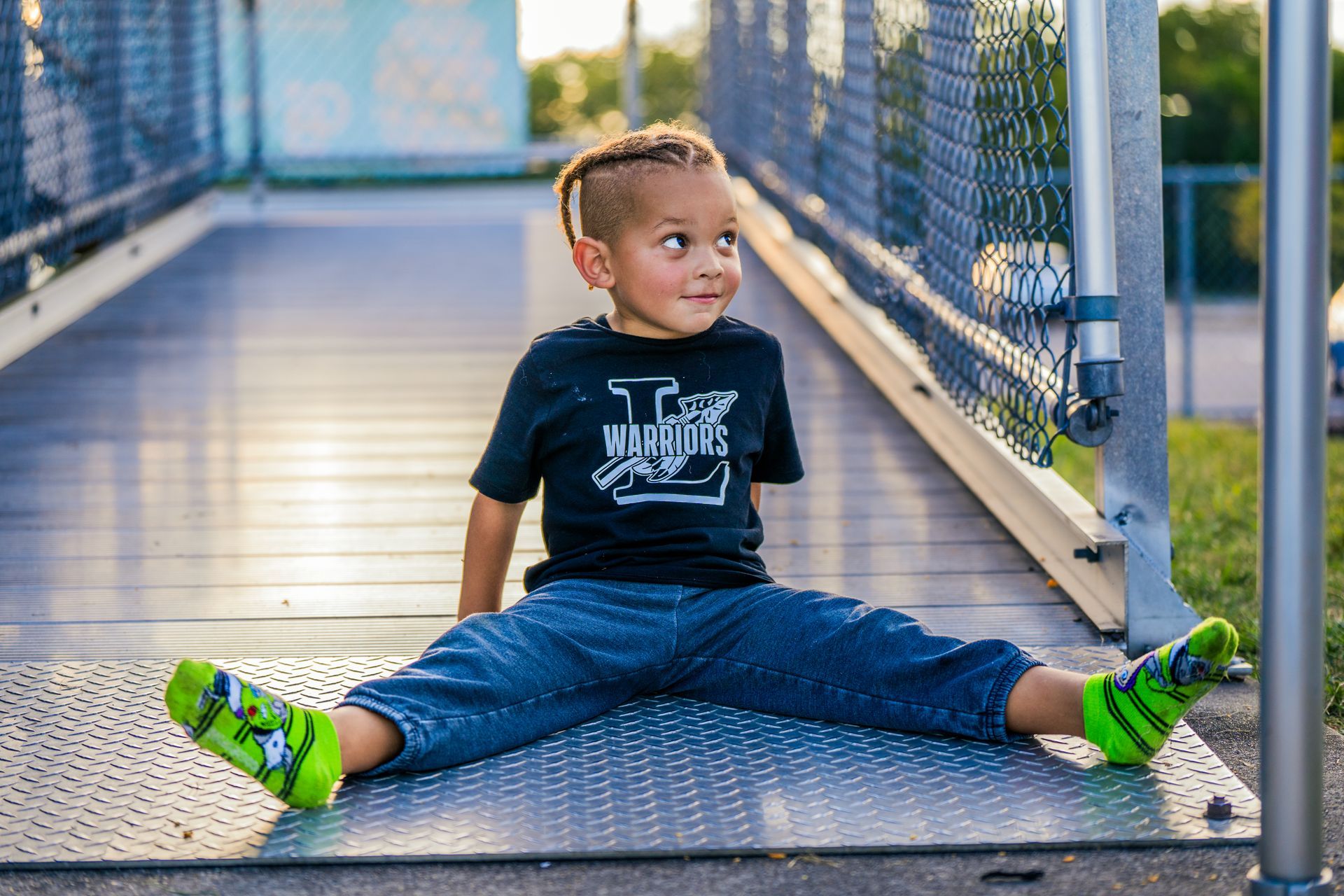 A young boy is sitting on the ground wearing green socks.