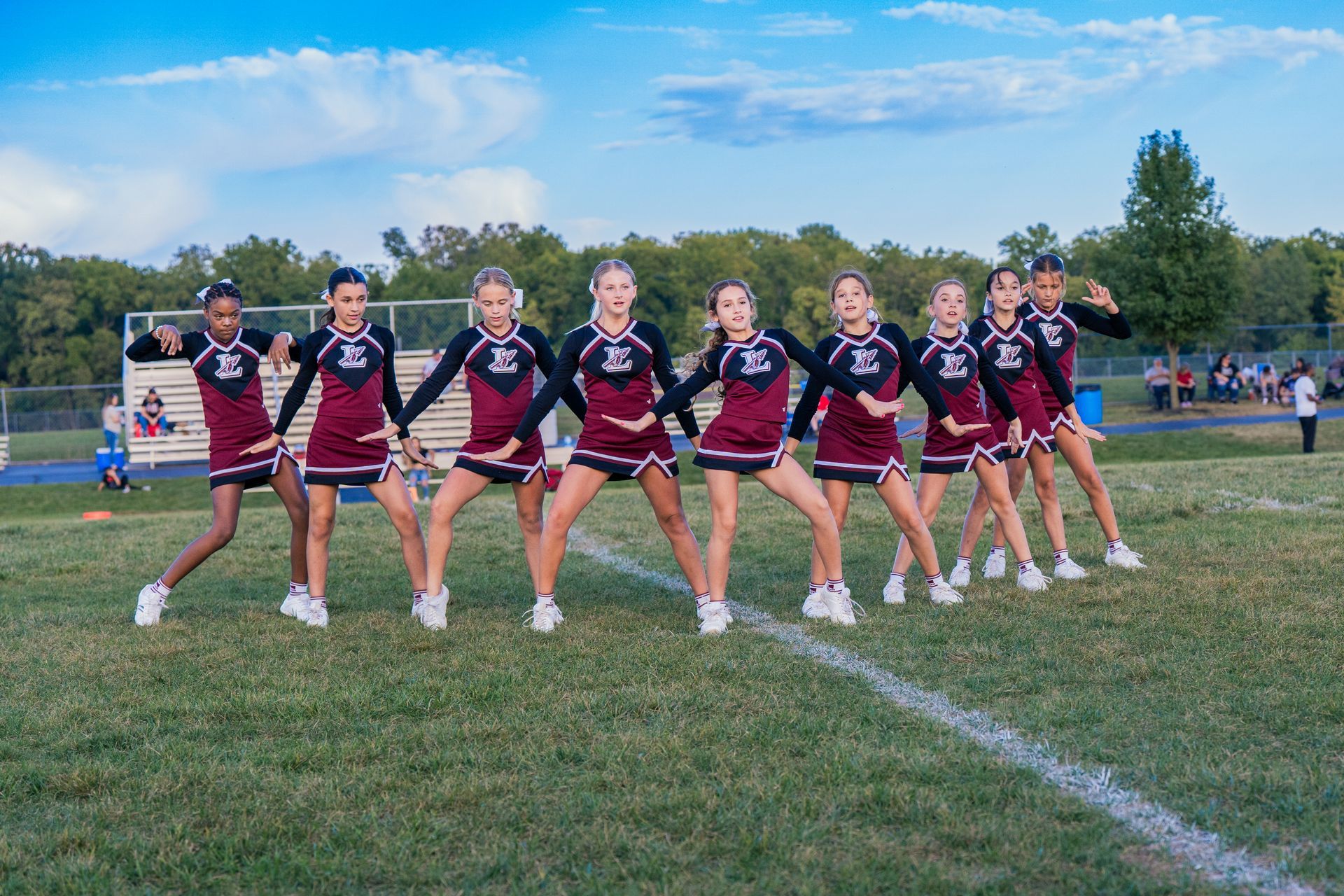 A group of cheerleaders are posing for a picture on a field.