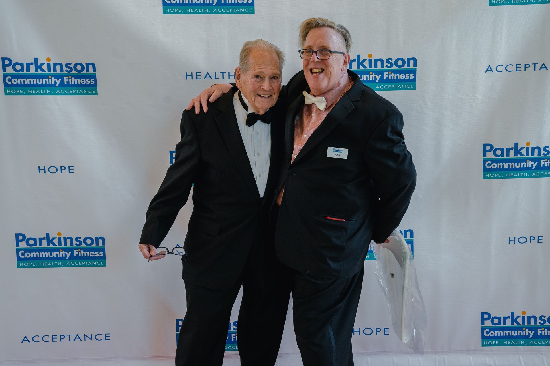 Two men are posing for a picture on a red carpet.