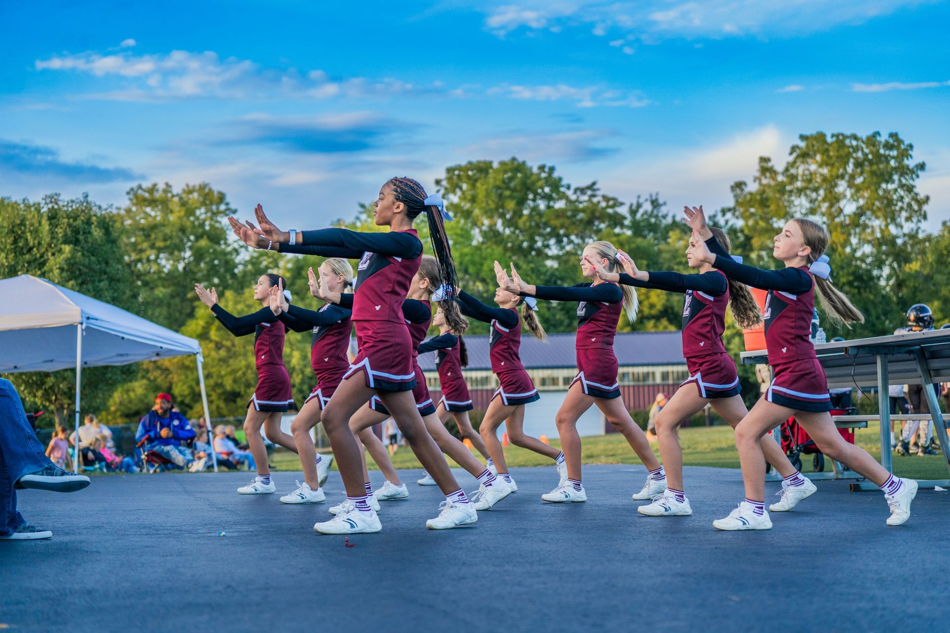 A group of cheerleaders are performing a dance on the street.