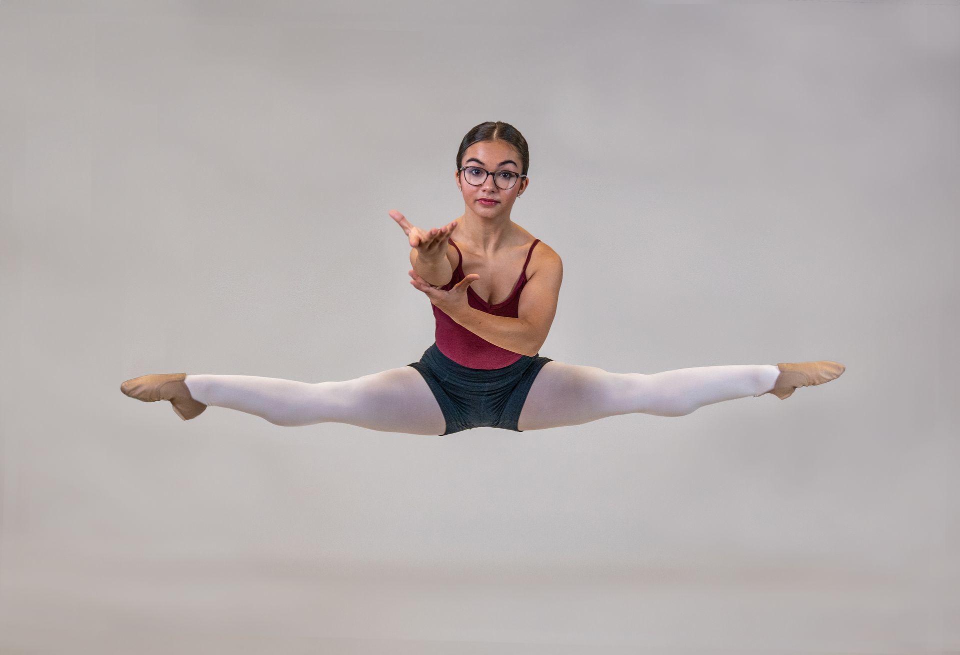 A young woman is doing a split in the air.