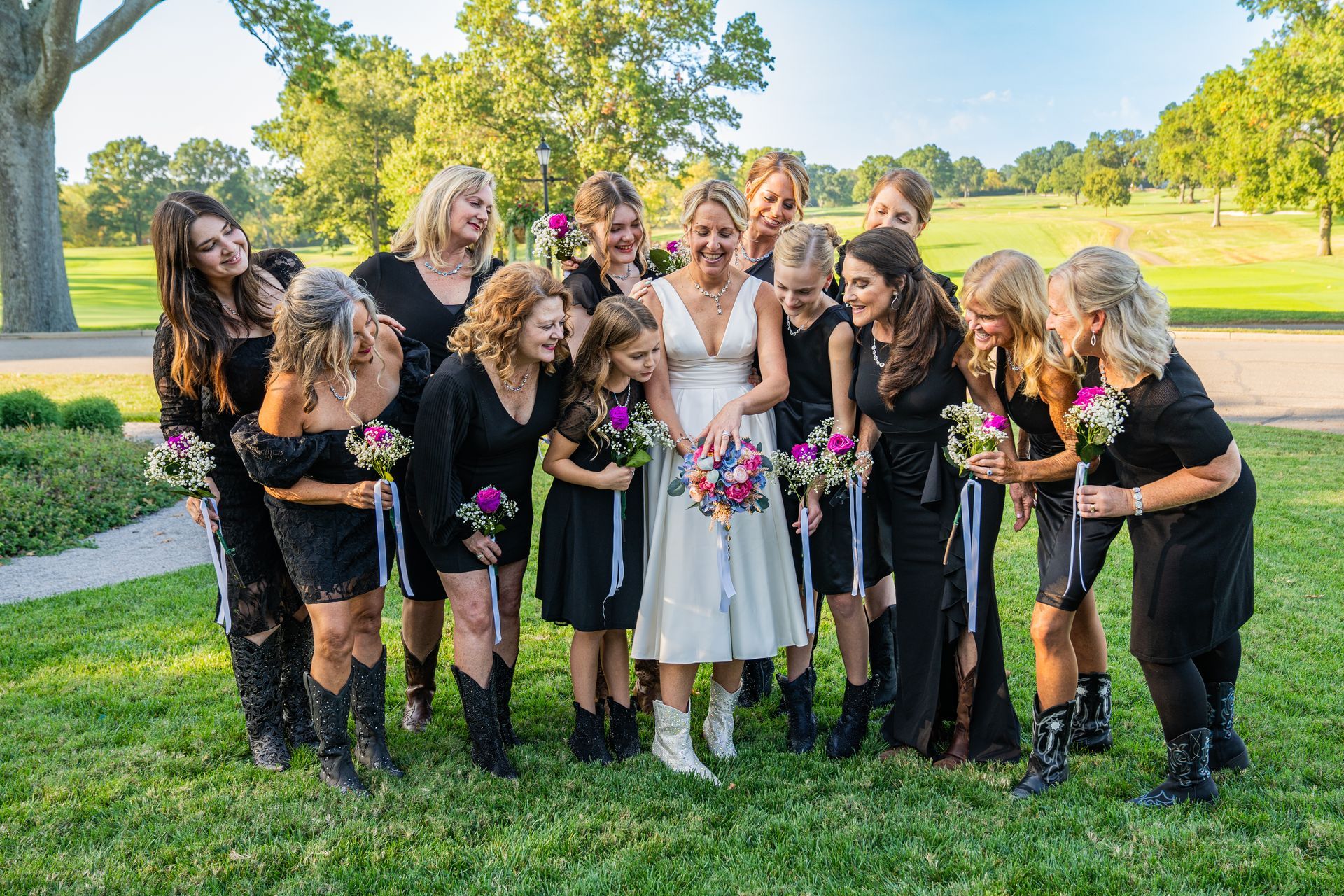 A bride and her bridesmaids are posing for a picture in the grass.