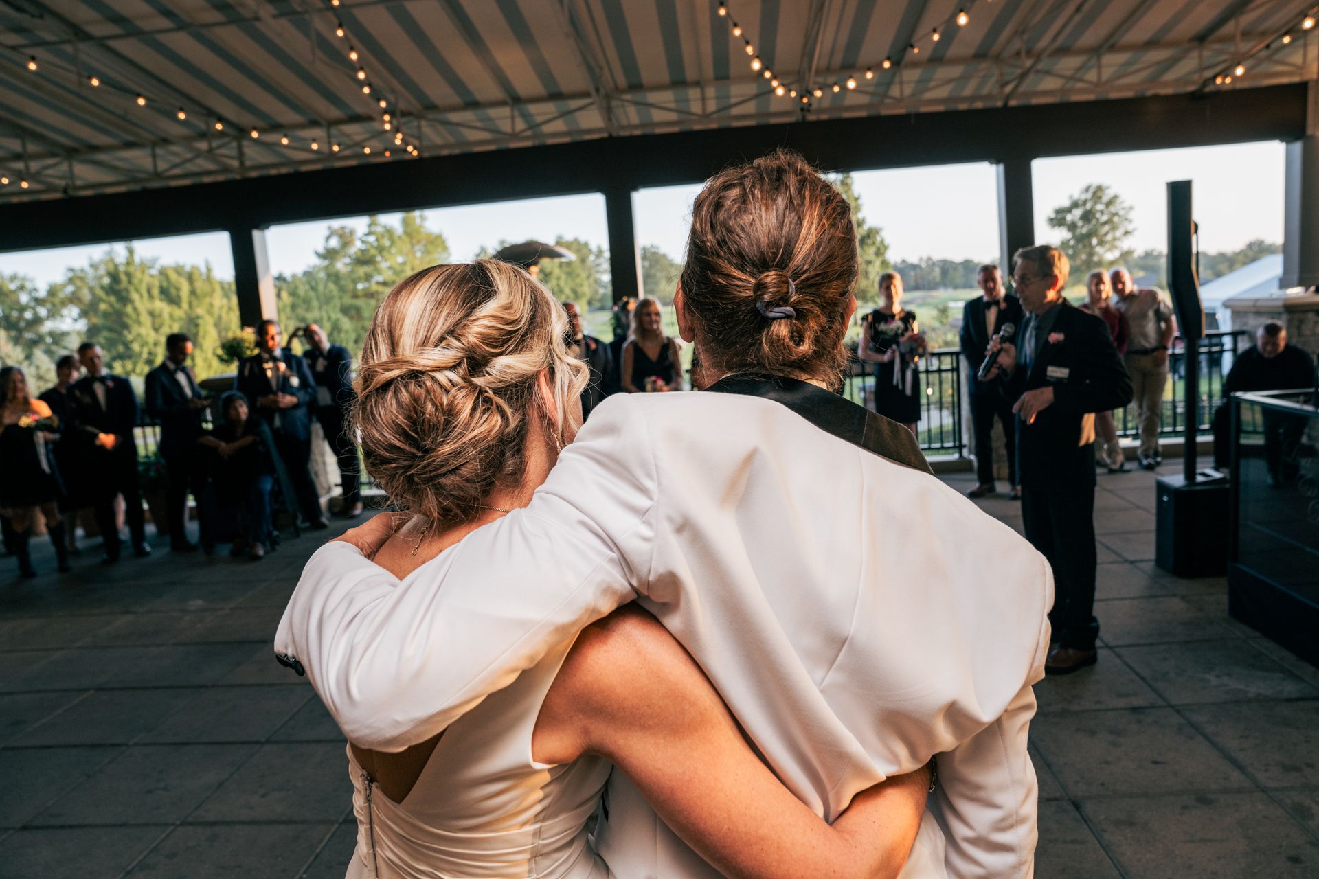 A bride and groom are hugging each other while dancing at their wedding reception.