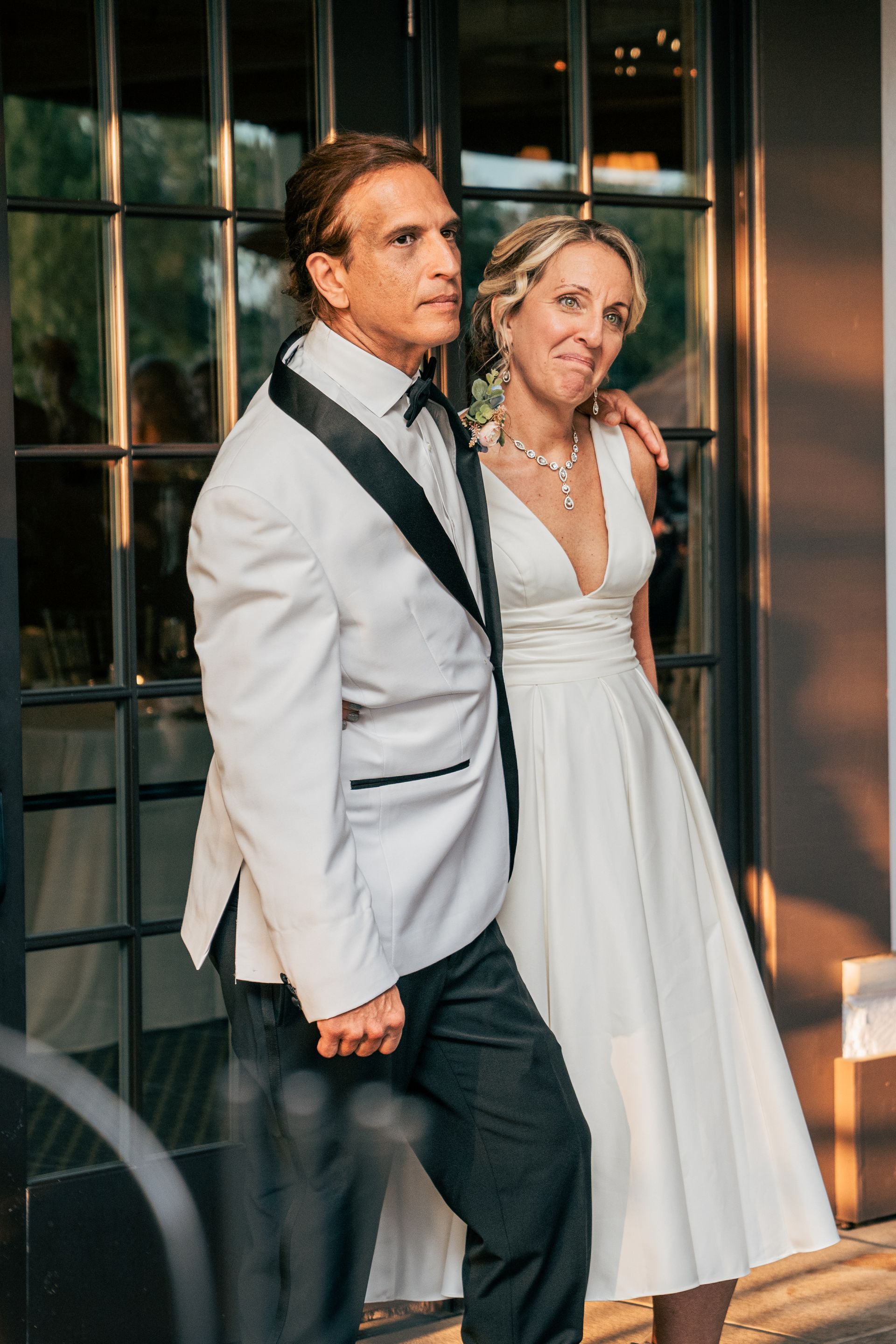 A man in a tuxedo and a woman in a white dress are standing next to each other.