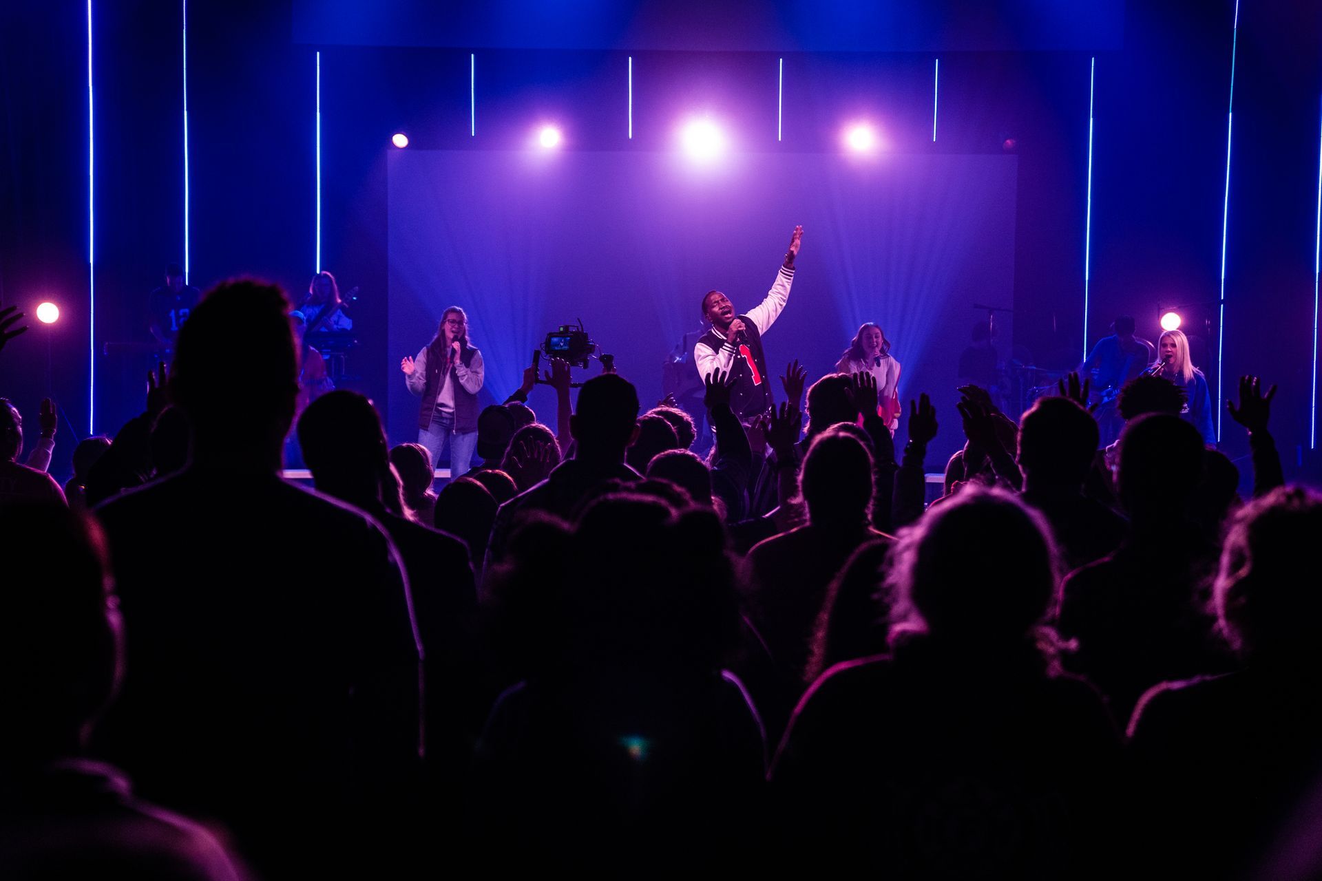 A group of people are standing in front of a stage at a concert.