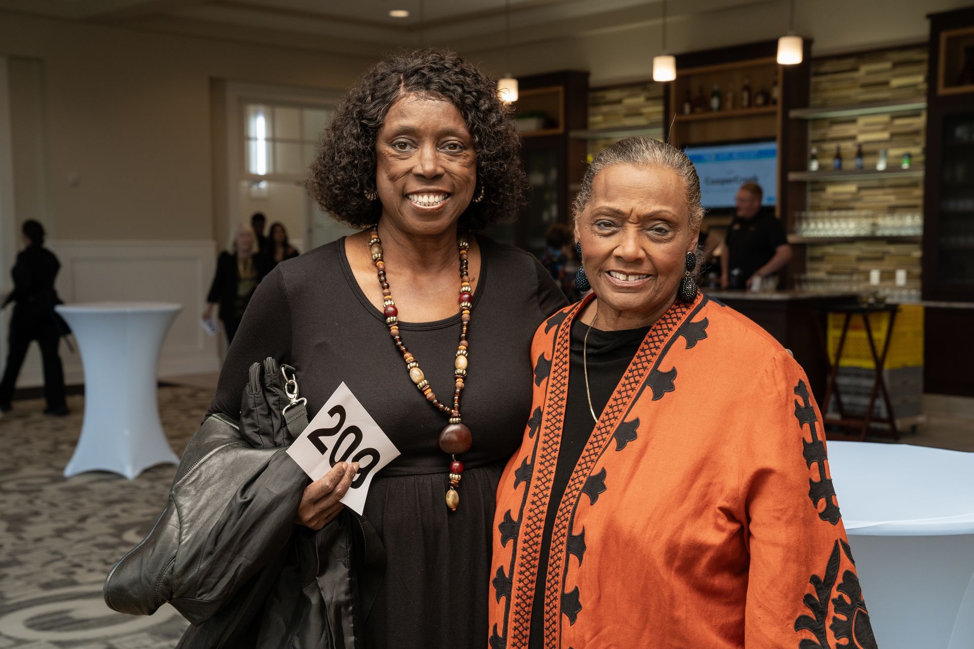 Two women are posing for a picture together in a room.