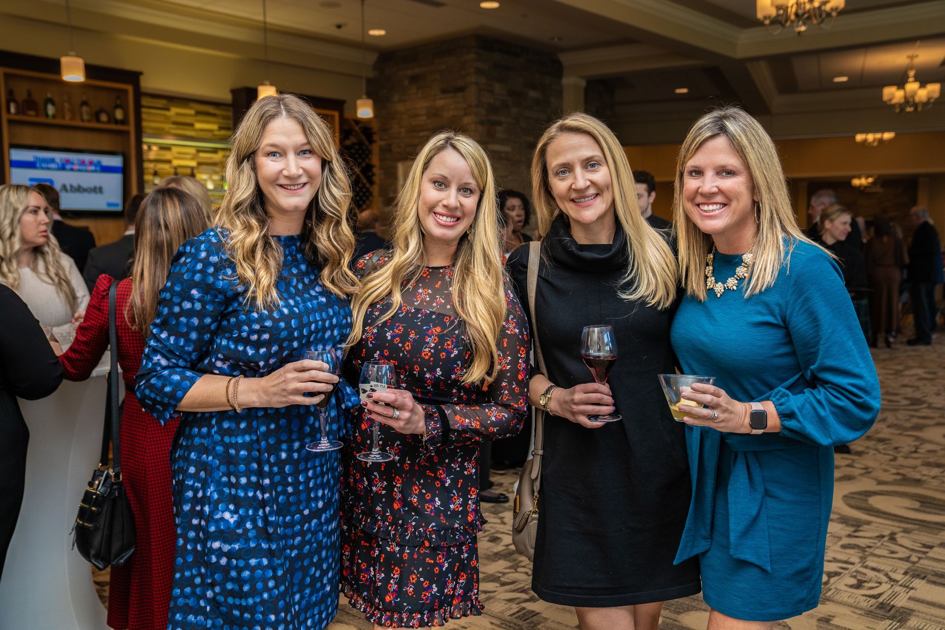 A group of women are posing for a picture while holding wine glasses.