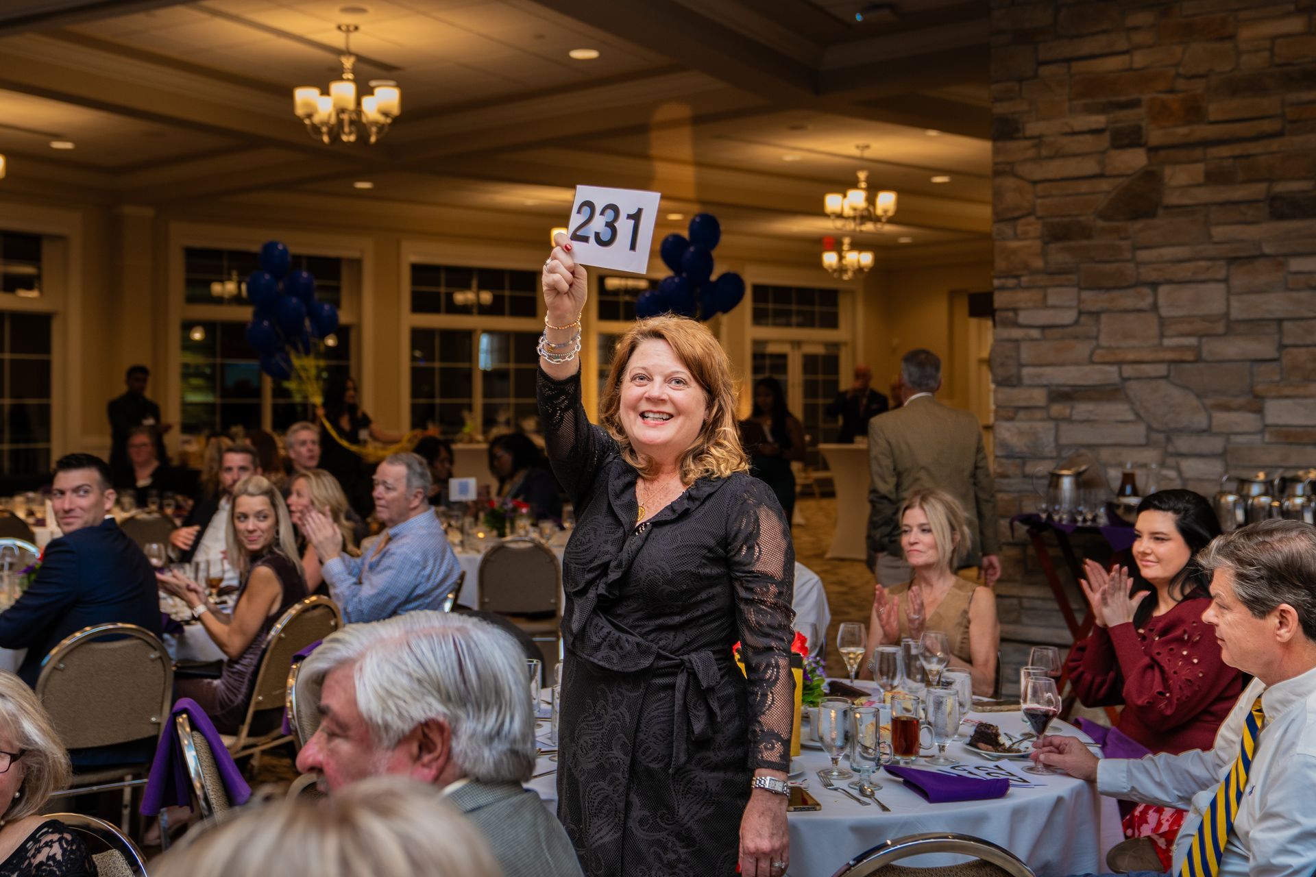 A woman is holding a sign that says 231 in front of a crowd of people.